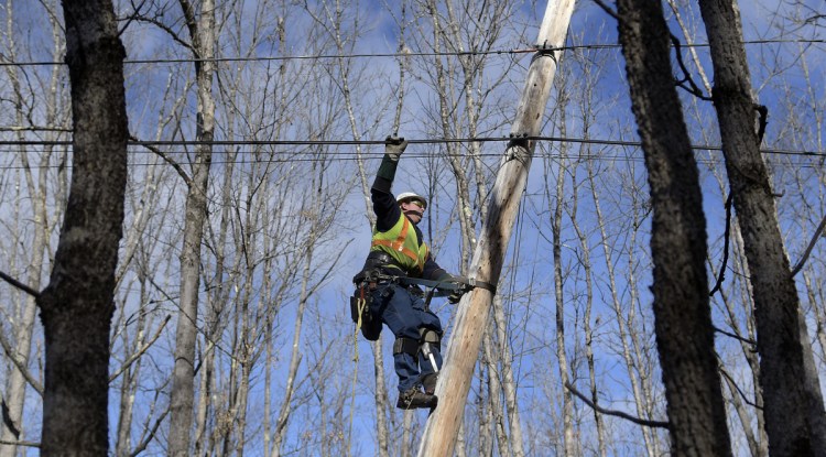 Central Maine Power lineman Sam Pottle scales a utility pole Sunday in Readfield. Pottle and his partner, George Marston, restored power at several locations in Kennebec County after wind knocked out service to thousands of customers.