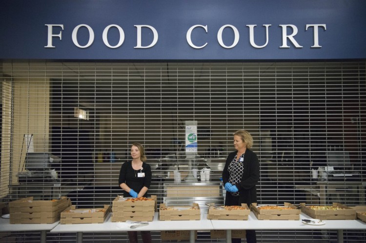 Heather Fellman, left, and Jennifer McCormack, right, wait to hand out pizza for dinner during a break in the community forum on overall health of Franklin County at Mt. Blue High School in Farmington on Oct. 25.