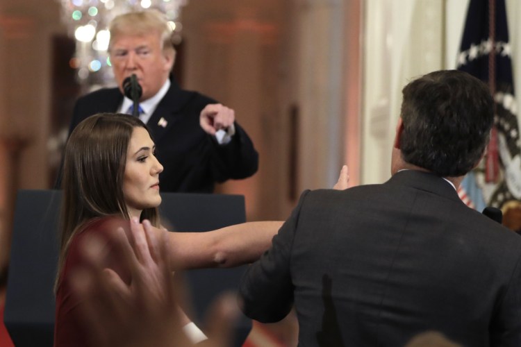 As President Trump points to CNN's Jim Acosta, a White House aide strips Acosta of the microphone while he questions the president during a news conference at the White House on Wednesday.