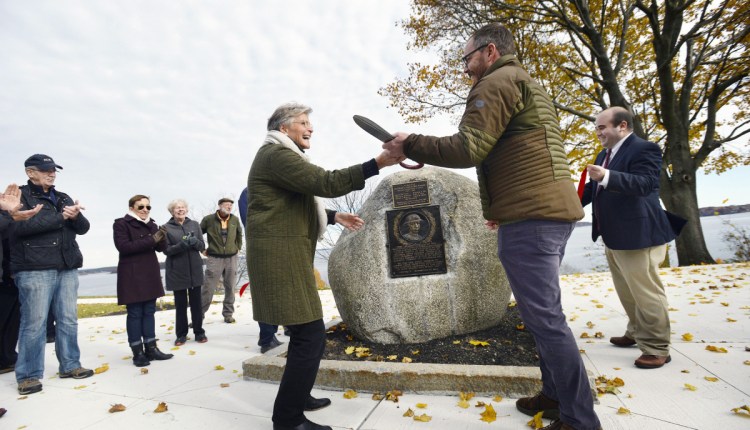 Patsy Wiggins, executive director of Friends of the Eastern Promenade, and Ethan Hipple, deputy director of Portland Parks, Recreation & Facilities, hold a giant pair of scissors after cutting the ribbon during the dedication of the Jacob Cousins Memorial on the Eastern Promenade in Portland on Friday.