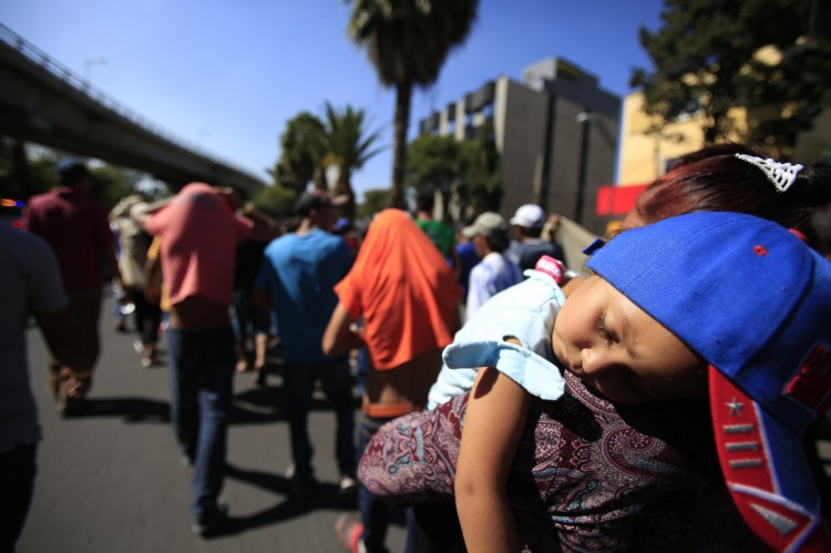 A sleeping Honduran girl is carried as a group of Central American migrants, representing the thousands participating in a caravan trying to reach the U.S. border, walk through Mexico City.