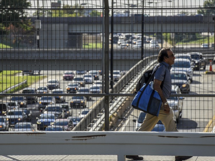 A pedestrian crosses over rush-hour traffic on the Southwest Freeway in Washington in September 2017. America's love affair with the automobile appears to be on the wane.