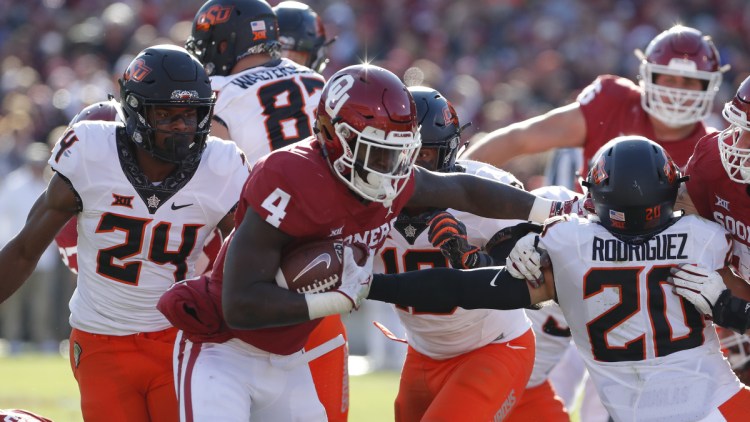 Oklahoma running back Trey Sermon escapes an attempted tackle by Oklahoma State safety Jarrick Bernard, left, and safety Malcolm Rodriguez during the Sooners' 48-47 win Saturday.
