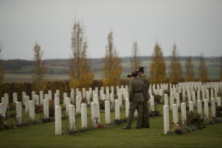 Two Australian soldiers walk along graves before a ceremony marking 100 years since the end of World War I, at the Australian National Memorial in Villers-Bretonneux, France, on Sunday.
