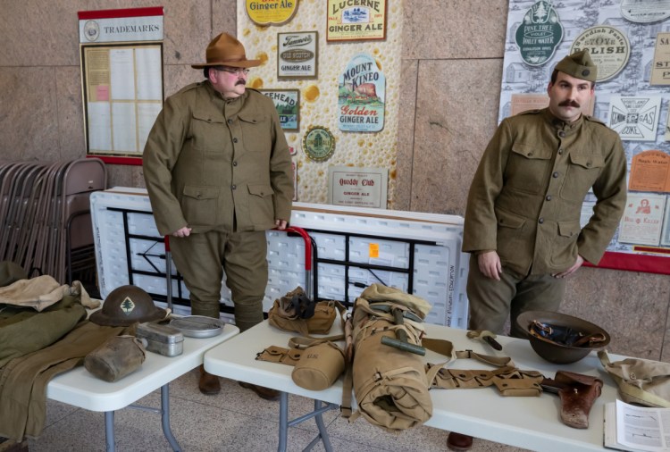 Dave Backus of Waldoboro, left, and his son Tom Backus of Warren wear period uniforms to display items that American soldiers carried in World War I during the Armistice Day Centennial Celebration in Augusta.