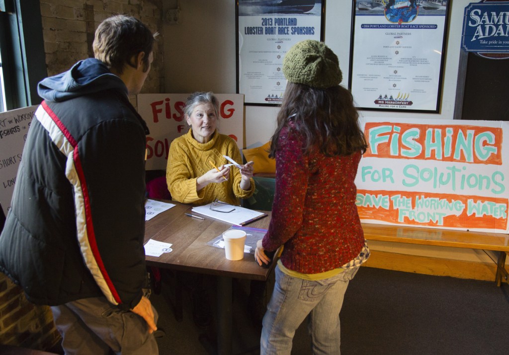 Volunteer Joanne Arnold of Falmouth offers raffle tickets to Stanislav Yurkuvich and Alex Fagan of Portland, during a petition drive and fundraiser at Andy's Old Port Pub on Sunday.