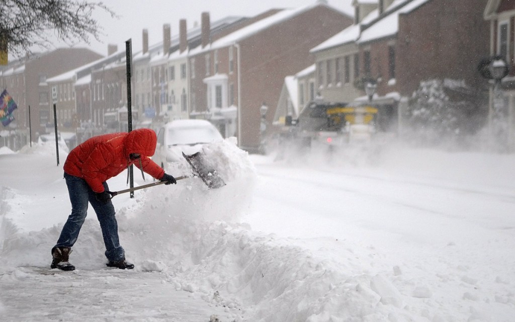 Nathan Sennett shovels snow of the sidewalk in front of his business in Hallowell in 2013.