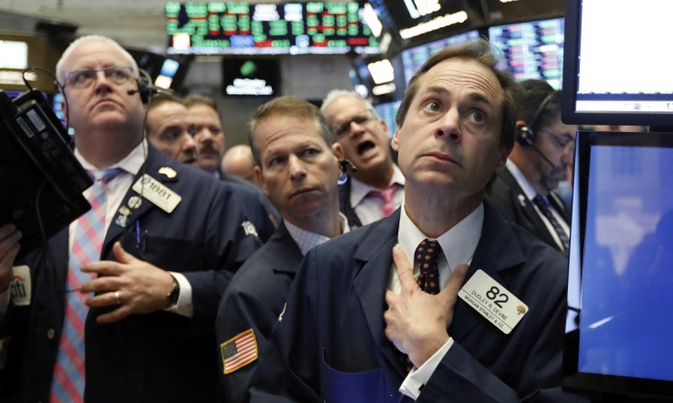 Dudley Devine, right, and other traders react to news Wednesday on the floor of the New York Stock Exchange.