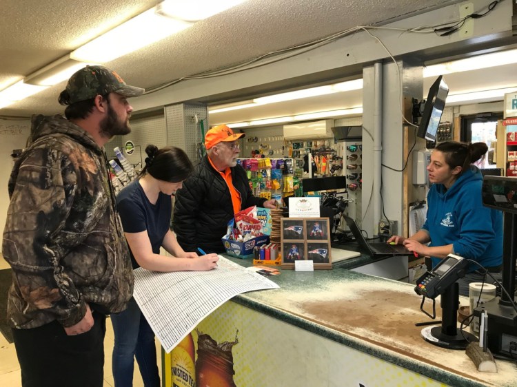 In West Gardiner, Four Corners General Store employees Dawn Hunt, right, and Jordan Shaw register Charles and Trevor Berry’s deer in October. Maine has a much smaller herd than most Southern or Midwest states, with about 230,000 to 250,000 deer.