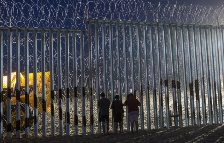 Children observe the movements of U.S. Border Patrol agents from Tijuana, Mexico, on Friday. Migrants were able to cross from Guatemala to Mexico with relative ease but now face the imposing U.S. border with its layers of fencing and vigilant law enforcement agents.