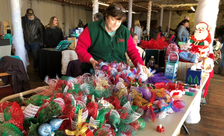 Pauline Day of Albion lays out holiday wreaths she made out of mesh ribbon at a craft fair at the Olde Mill Place in Vassalboro on Saturday.