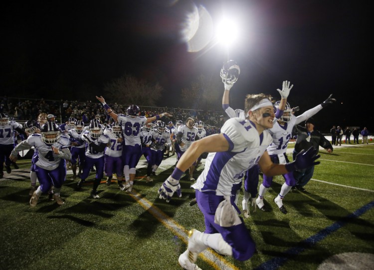 Marshwood players rush onto the field to celebrate their 49-0 victory over Brunswick in the Class B state championship game Saturday night at Fitzpatrick Stadium.