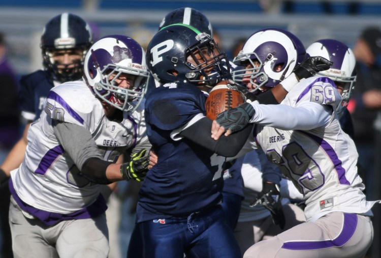 Last year Blaize Vail, left, and Jason Pichette of Deering put the squeeze on Terion Moss and Portland, to win 22-20. This year's game will be played a day early with a frigid holiday forecast.