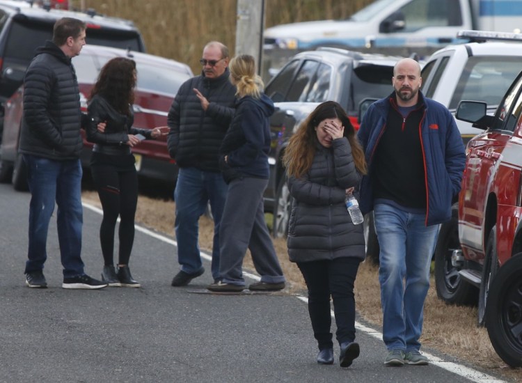 Pedestrians walk away from the scene of a fatal fire in Colts Neck, New Jersey, on Tuesday. Authorities say two adults and two children were found dead at the burning mansion near the New Jersey shore.