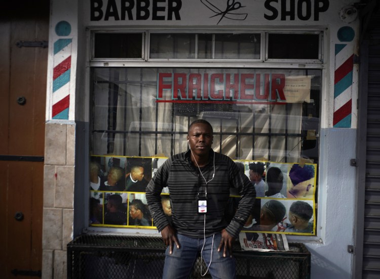 Philocles Julda, 44, stands in front of a Haitian barbershop in Tijuana, Mexico. Julda belongs to a group of Haitian immigrants who offer their peers resources such as language lessions and money management tips.