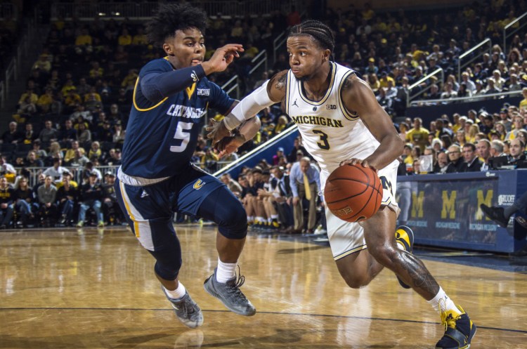 Chattanooga guard Donovann Toatley, left, defends against Michigan guard Zavier Simpson during the Wolverines' 83-55 win Friday in Ann Arbor, Mich.