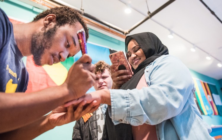 African Youth Alliance Vice President Djamal Maldoum draws henna on Hani Mohamed of Auburn during Friday's open house at the new organization's "welcoming place" on Lisbon Street in Lewiston.