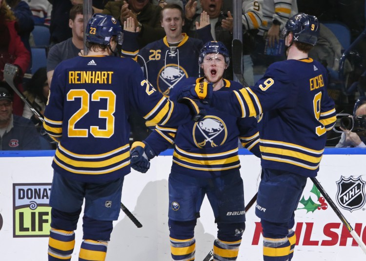 Jeff Skinner, center, is met by Buffalo teammates Sam Reinhart and Jack Eichel after scoring in the third period of an overtime win Friday.