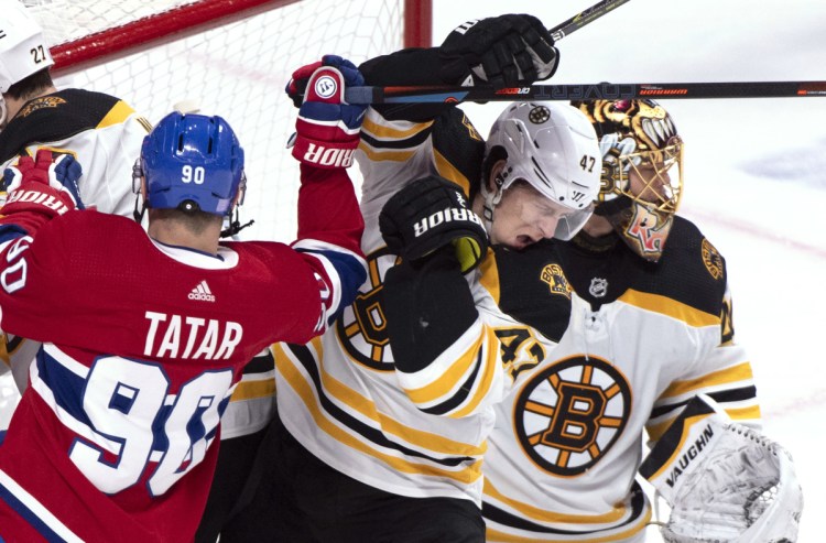 Torey Krug of the Bruins takes a hit from the Montreal's Tomas Tatar in front of Bruins goaltender Tuukka Rask during the first period of Saturday's game in Montreal. Boston won 3-2.