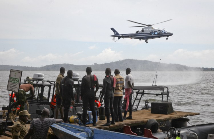 Ugandan divers look up as a helicopter searches for victims of a boat that capsized in Lake Victoria near Kampala, the capital of Uganda, on Sunday.