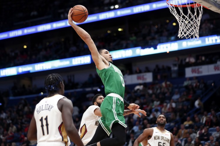 Celtics forward Jayson Tatum goes to the basket over Pelicans guard Jrue Holiday, 11, forward Anthony Davis, center, and guard E'Twaun Moore in the second half of the Celtics' 124-107 win Monday in New Orleans.