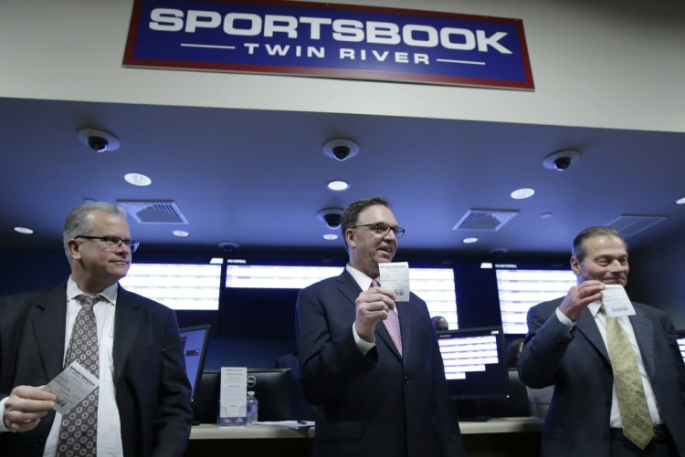 Rhode Island House Speaker Nicholas Mattiello, Twin River executive John Taylor and Rhode Island Senate President Dominick Ruggerio, right, display tickets after placing the first legal sports bets Monday at Twin River Casino Hotel, in Lincoln, R.I.