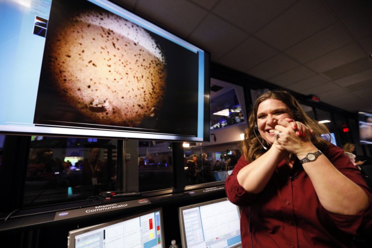 An engineer at NASA's Jet Propulsion Laboratory celebrates next to an image of Mars sent from the InSight lander shortly after it landed on the red planet Monday. Only about 40 percent of Mars landings are successful.
