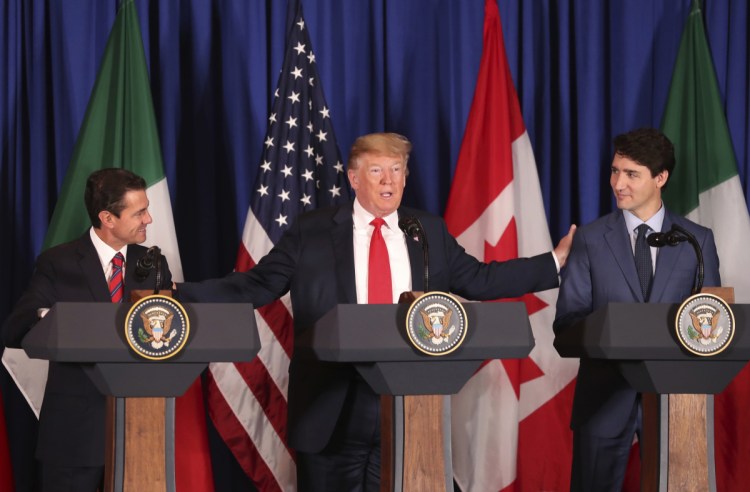 President Trump reaches out to Mexico's President Enrique Pena Nieto, left, and Canada's Prime Minister Justin Trudeau as they prepare to sign a new United States-Mexico-Canada Agreement that is replacing the NAFTA trade deal, during a ceremony at a hotel before the start of the G-20 summit in Buenos Aires, Argentina, on Friday.