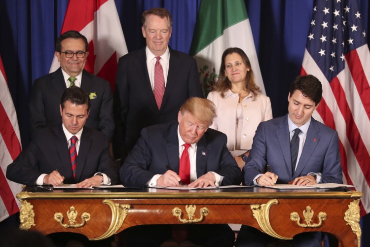 President Trump sits between Canada's Prime Minister Justin Trudeau, right, and Mexico's President Enrique Pena Nieto as they sign the United States-Mexico-Canada Agreement, which is replacing the NAFTA trade deal, during a ceremony Friday at a hotel before the start of the G20 summit in Buenos Aires, Argentina. The USMCA, as Trump refers to it, still needs approval by lawmakers in all three countries.