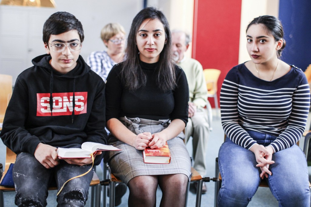Sisters Hayarpi, 21, right, Warduhi, 19, center, and their 15-year-old brother, Seyran Tamrazyan, pose for a photo inside the Bethel Church in The Hague, Netherlands, where a rotating roster of preachers has led a nonstop service.