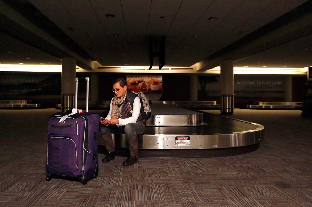 Mary Tippet, who had just arrived at Portland International Jetport from her home state of Colorado, waits for her ride to arrive in the baggage area under emergency lighting. Her friends were stuck in heavy traffic when part of Congress Street was closed after a truck hit a utility pole, causing a power outage at the jetport and nearby areas. 