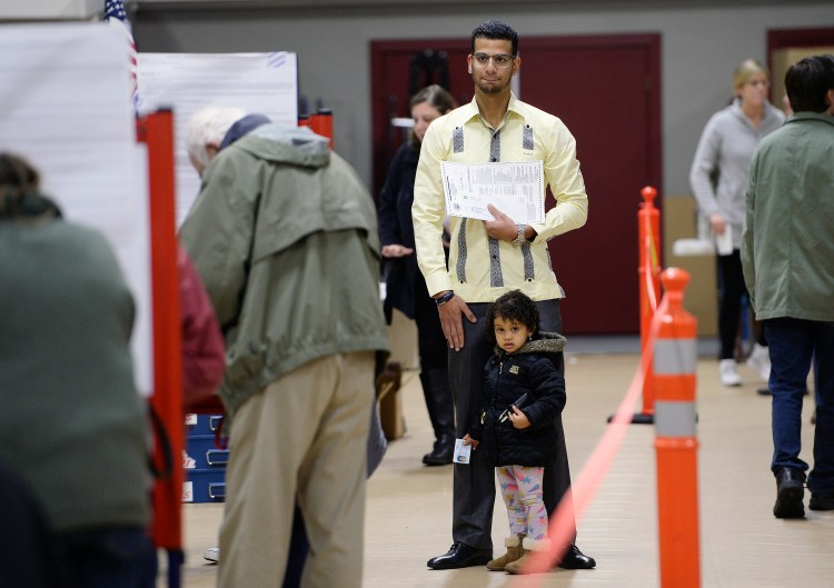 Luis Sanchez waits for a voting booth to open up as he votes with his daughter Sophia, 2, at the Saco Community Center on Tuesday. It was the first vote in a U.S. election for Sanchez, who is originally from the Dominican Republic and became an American citizen on Nov. 2. He took his time filling out his ballot as Sophia played around his feet.