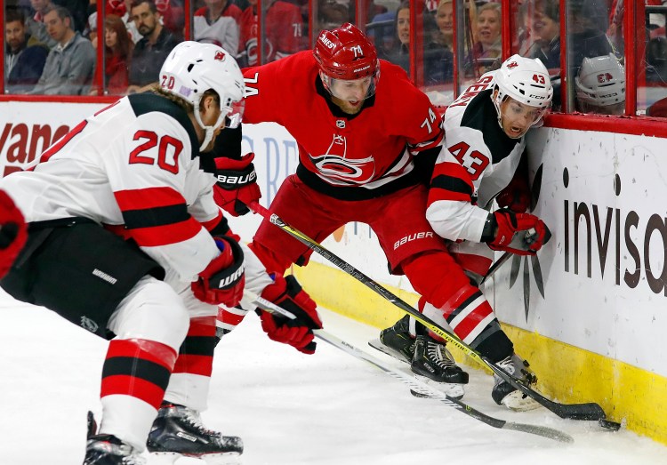 Carolina's Jaccob Slavin (74) battles between New Jersey Devils' Blake Coleman (20) and Brett Seney (43) during the first period of the Hurricanes' 2-1 win Sunday in Raleigh, North Carolina.