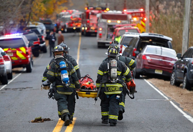 Firefighters carry a stretcher to the scene of a fatal fire Tuesday in Colts Neck, N.J. 