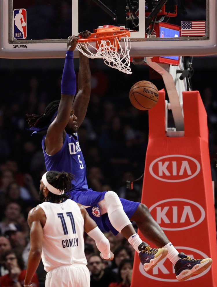 Los Angeles Clippers' Montrezl Harrell, top, dunks while being defended by Memphis Grizzlies' Mike Conley (11) during the first half Friday in Los Angeles.