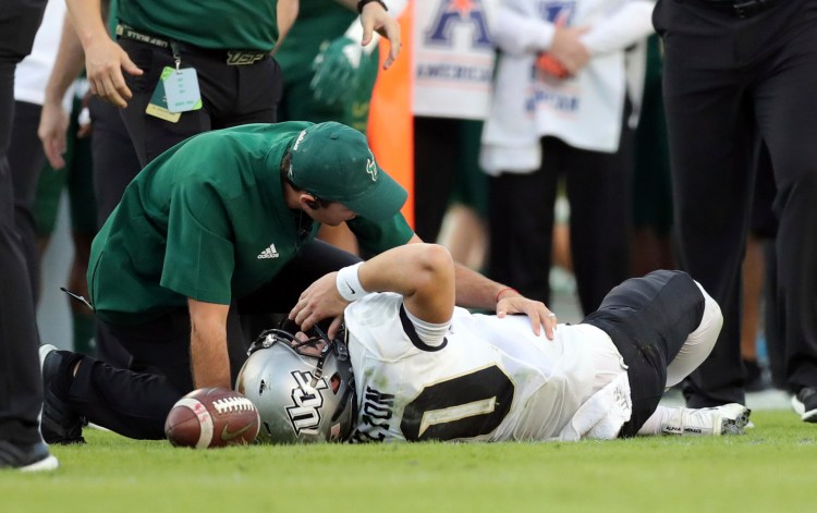 A trainer from South Florida attends to Central Florida quarterback McKenzie Milton after he went down with an apparent knee injury during the first half Friday in Tampa, Florida.