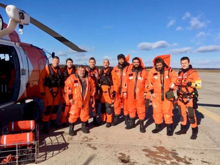 The Air Station Cape Cod rescue air crews and the four fishermen they rescued from the fishing boat Aaron & Melissa II pose for a group photograph at Brunswick Executive Airport in Brunswick on Wednesday. The fishing crew abandoned ship about 60 miles off the coast of Rockland.