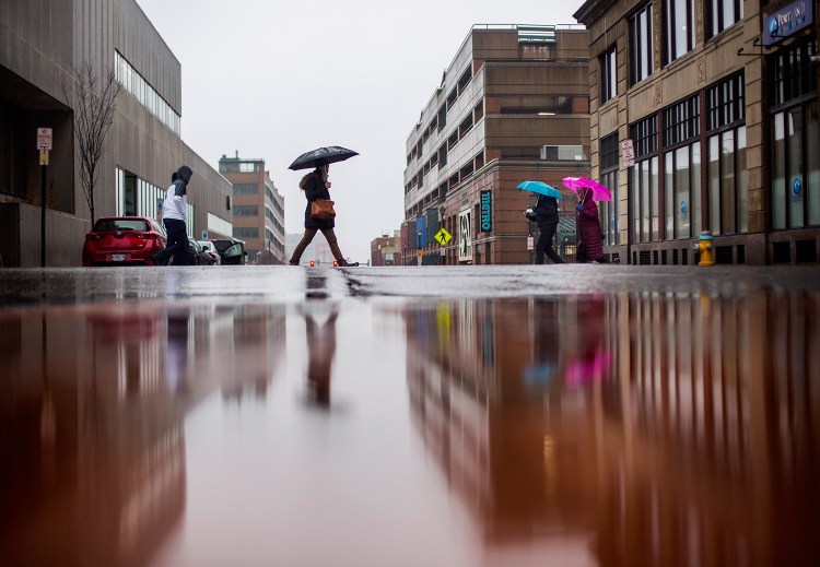 Pedestrians cross the intersection of Congress and Elm streets in Portland on a wet Friday.