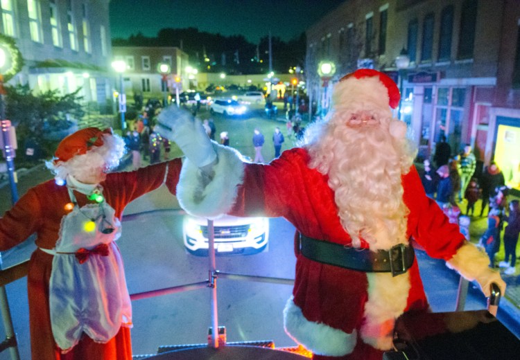 Mrs. Claus and Santa Claus wave at spectators Saturday as they ride down Water Street on the Gardiner Fire Department's Ladder 1 truck in Gardiner. Staff photo by Joe Phelan