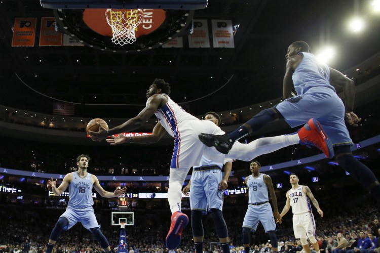 Joel Embiid of the Philadelphia 76ers, center, goes up for a shot after slipping past JaMychal Green of the Memphis Grizzlies during the first half of Philadelphia's 103-95 victory Sunday night.
