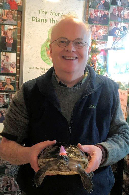 Diane the Turtle, wearing a party hat, celebrates her 50th birthday with her owner, Jim Tonner, at a gift shop he and his brother Brad run in Bristol, N.H. The turtle was given to Jim Tonner when he was 12 and being treated for hip arthritis at his home in Braintree, Mass. (Brad Tonner via AP)