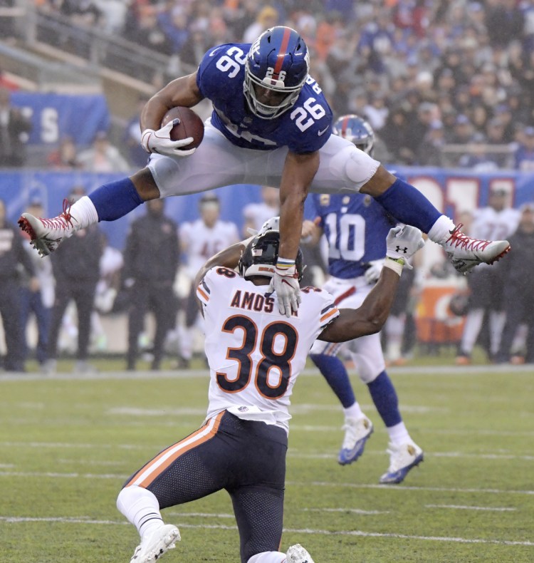 Giants running back Saquon Barkley leaps over Bears strong safety Adrian Amos on a 17-yard reception during New York's 30-27 win on Sunday.