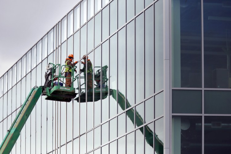 Anthony Richards trims out newly installed windows last week at the Wex building that's under construction on Thames Street in Portland. CMP billed a company working on the building for only a fraction of the 43,000 kilowatt-hours it used.