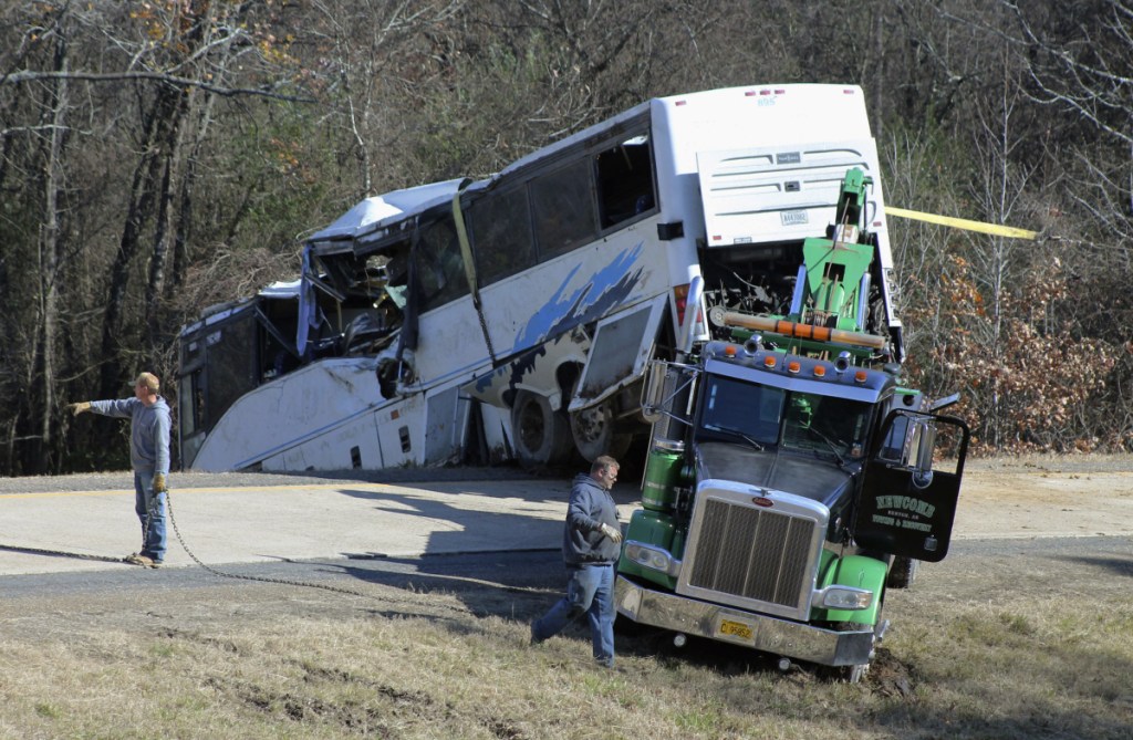 Employees from a wrecker service work to remove a charter bus from a roadside ditch Monday after it crashed alongside Interstate 30 near Benton, Ark. The bus was carrying a youth football team from Tennessee when it rolled off an interstate off-ramp and overturned before sunrise Monday. The elementary-school age football team from Orange Mound Youth Association in southeast Memphis had played in a tournament in Dallas over the weekend.