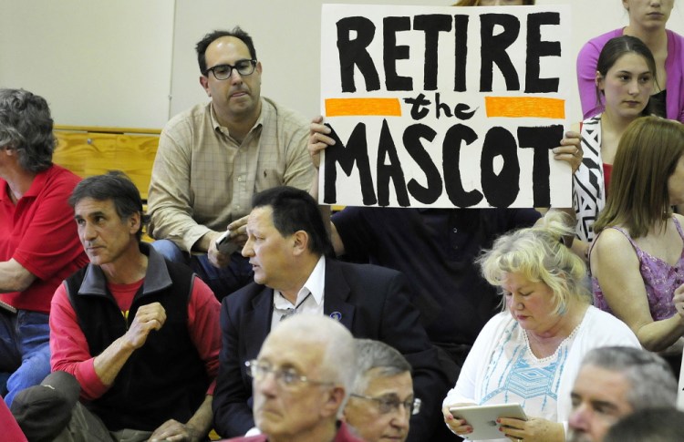 Mark Roman holds a sign protesting use of the name Indian for SAD 54 sports teams during a forum in 2015 in Skowhegan. At far left is former chief of the Penobscot tribe Barry Dana, of Solon.