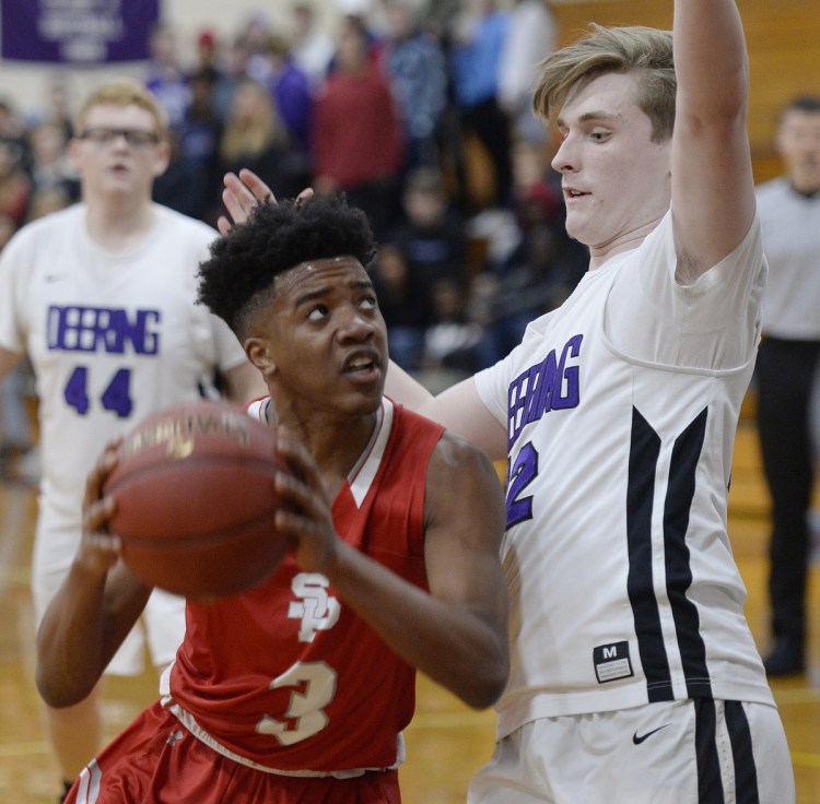 Tyree Bijokta of South Portland drives to the basket against Cole Martinson of Deering during their season-opening boys' basketball game Friday night at Deering High. Deering came away with a 53-40 victory.