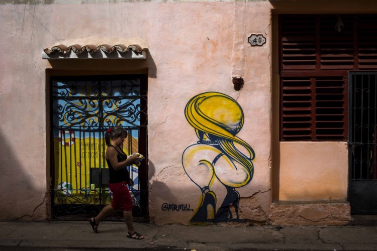 A woman passes by a closed art store decorated by a mural in Havana, Cuba, on Dec. 5. Associated Press/Desmond Boylan