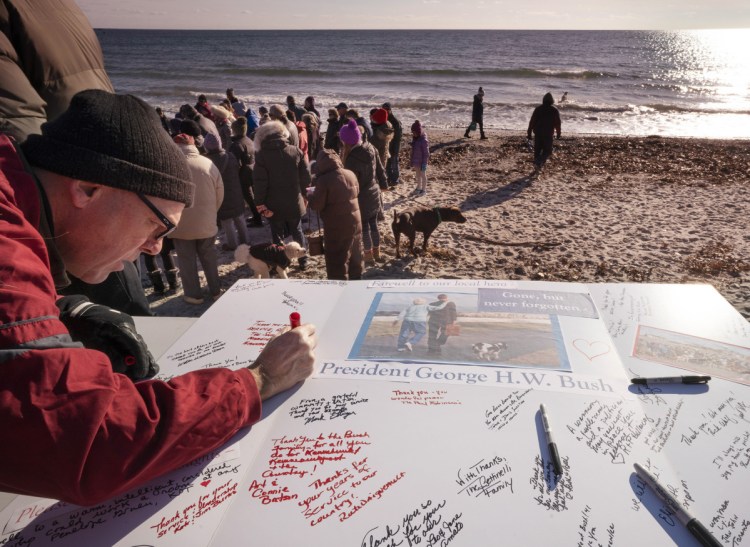 Chris Snow of Kennebunk signs a card in honor of the late President George H.W. Bush at Gooch's Beach in Kennebunk on Sunday. About 200 people gathered at the beach with their dogs to sign the card and share remembrances of the 41st president and his wife, Barbara. Mrs. Bush often walked her dogs on the beach.