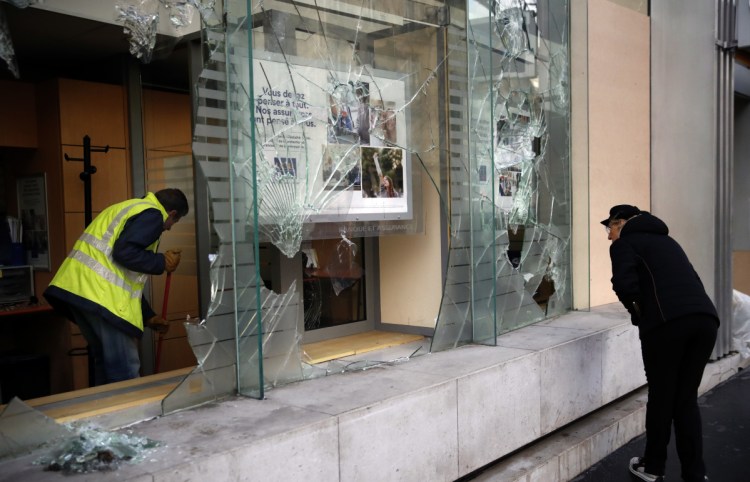 A worker clears debris from a Paris bank on Sunday as the city cleaned up from protests.