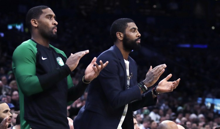 Boston Celtics guard Kyrie Irving, right, who did not play due to an injury, and guard Brad Wanamaker, left, applaud teammates during the first quarter of the Celtics' 113-110 win over New Orleans on Monday in Boston.